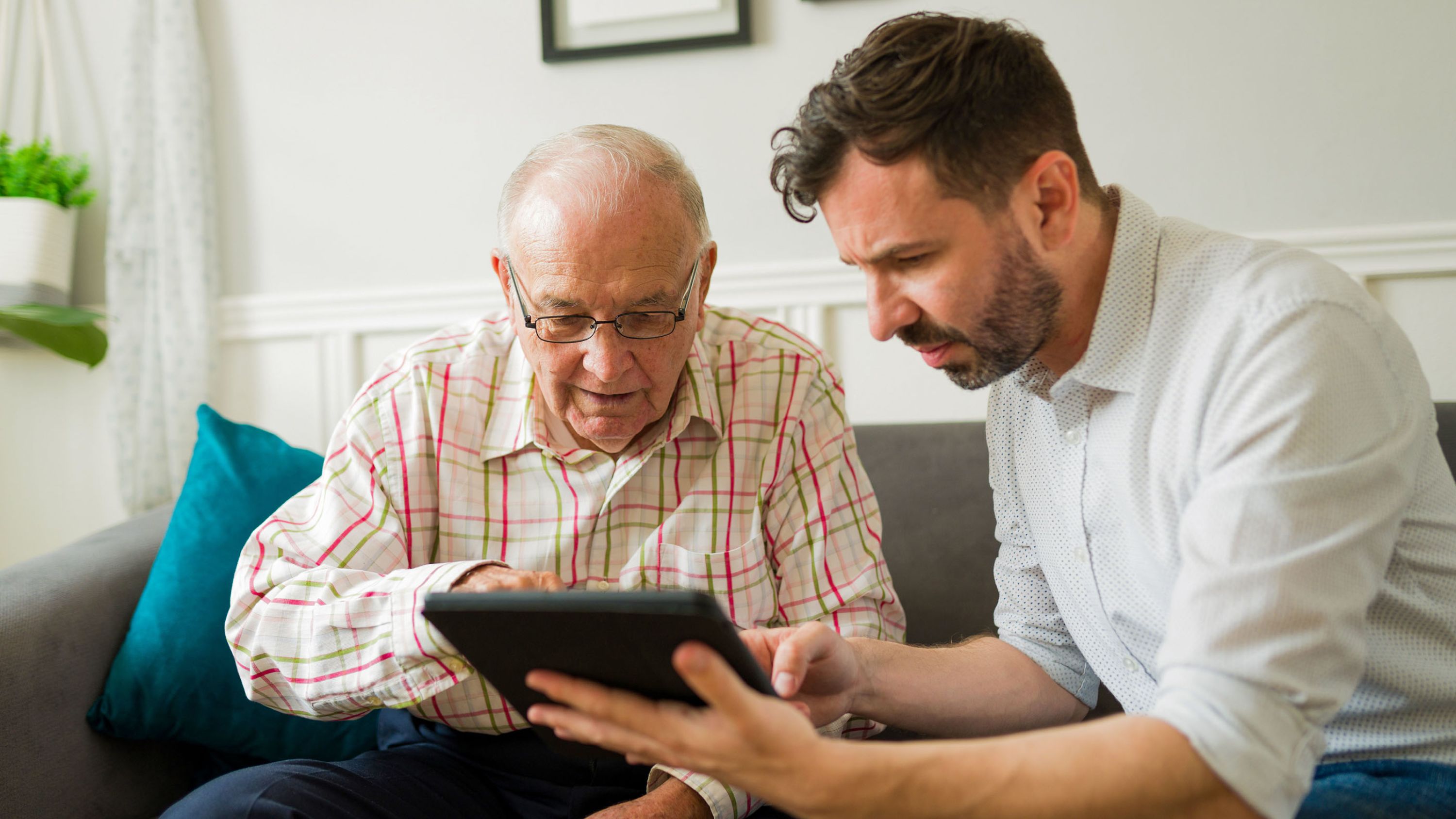 Freiwilliger erklärt Senior etwas am Tablet.