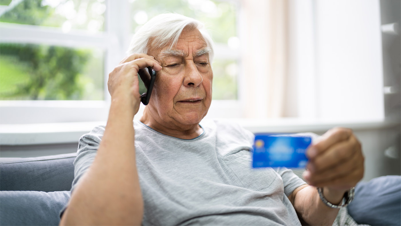 Ein Mann ist am Telefon und hat eine Kreditkarte in der Hand