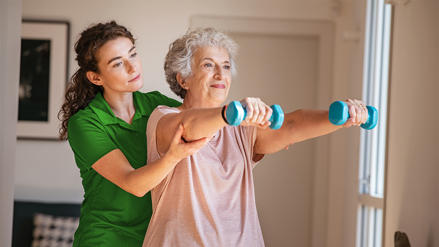 Eine Seniorin macht mit ihrem Domi Gym Coach zu Hause Sport